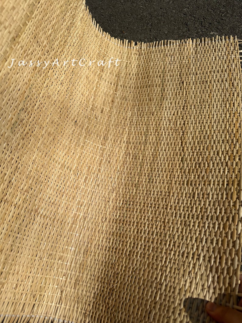 Pode incluir: Um close-up de um tapete tecido de fibra natural. O tapete &eacute; feito de um material marrom claro e tem um padr&atilde;o tecido. O tapete est&aacute; dobrado ao meio, mostrando o interior e o exterior da trama.