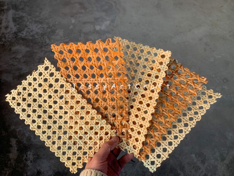 May include: Several woven rattan placemats in varying shades of tan and orange are displayed. The placemats have a geometric pattern of intersecting lines and circular openings. The text "Tossy Art Craft" is visible in the image.