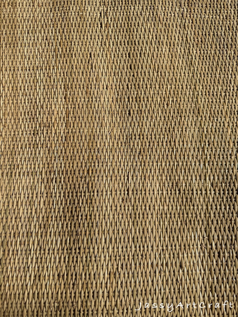 Pode incluir: Um close-up de um tapete tecido feito de materiais naturais. O tapete tem uma cor castanho claro e uma superf&iacute;cie texturizada. O padr&atilde;o de tecelagem &eacute; vis&iacute;vel e cria um padr&atilde;o diagonal.