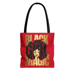 May include: Red tote bag with a gold design that says "Black Girl Magic". The design features a silhouette of a Black woman with an afro.