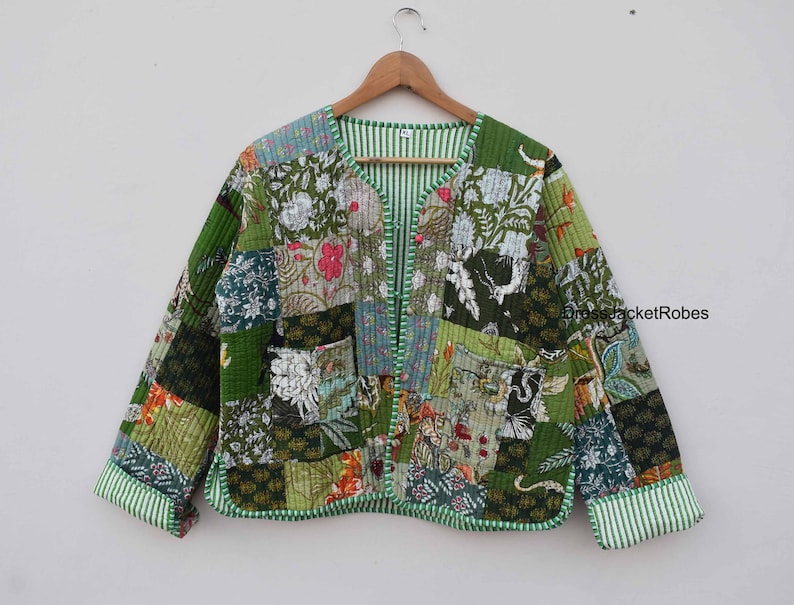 May include: A green patchwork jacket with a floral print. The jacket has a V-neck and a button closure. The sleeves are long and have a striped trim.