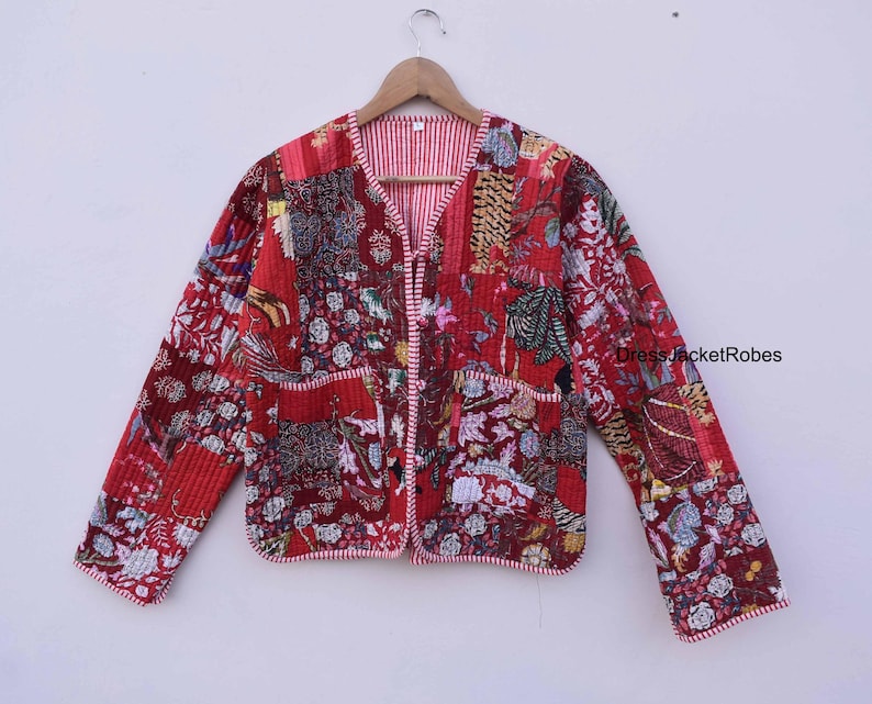 May include: Red quilted jacket with a floral print and a white and red striped lining. The jacket has a V-neck and a button closure. DressJacketRobes is printed on the right sleeve.