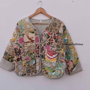 May include: A patchwork quilted jacket with a floral print in shades of pink, green, blue, and yellow. The jacket has a V-neck and a button closure. The fabric is a soft cotton blend.