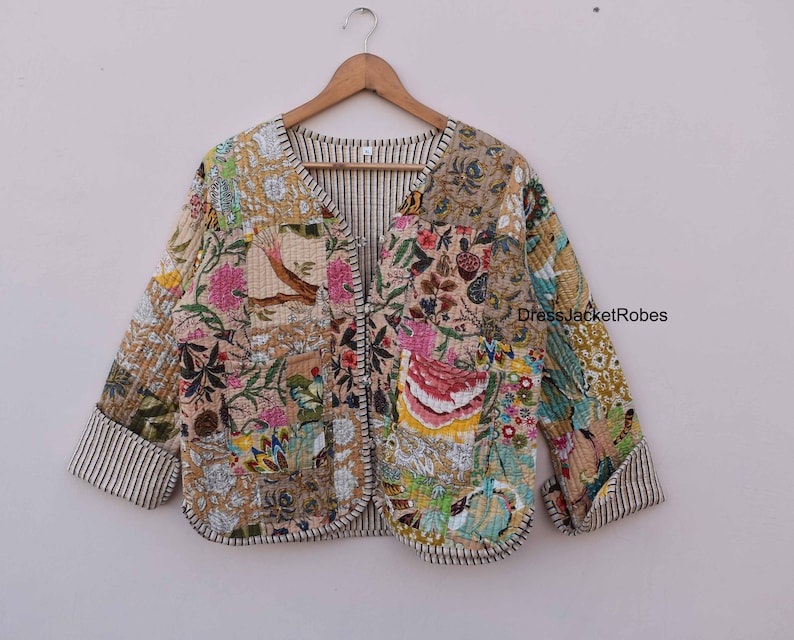 May include: A patchwork quilted jacket with a floral print in shades of pink, green, blue, and yellow. The jacket has a V-neck and a button closure. The fabric is a soft cotton blend.