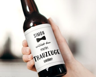 May include: A brown glass beer bottle with a white label that says "SIMON willst du mein TRAUZEUGE werden?" with a black bow tie icon.