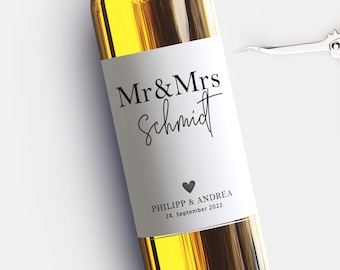 May include: White wine bottle with a wedding label that says "Mr & Mrs Schmidt" with a small heart and the date "24. September 2022" and the names "Philipp & Andrea".