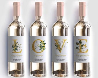 Puede incluir: Cuatro botellas de vino blanco con etiquetas de lámina dorada. Cada etiqueta presenta una letra dorada de la palabra "LOVE" con un diseño floral y el texto "Laura & Fabian" y "18 de octubre de 2023".
