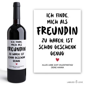 Könnte beinhalten: Eine Flasche dunkler Rotwein mit einem weißen Etikett und schwarzem Text. Auf dem Etikett und einer passenden Karte steht "ICH FINDE, MICH ALS FREUNDIN ZU HABEN, IST SCHON GESCHENK GENUG." Die Karte enthält auch ein rotes Herz.