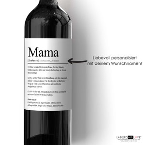 May include: A wine bottle label with the word "Mama" in large, bold letters. The label also includes the definition of the word "Mama" as a noun, along with a description of a strong, loving mother. The text on the label reads: "Mama [Stefanie] /Substantiv, feminin (1) Eine unglaublich starke Frau, die ihre Kinder bedingungslos liebt und sie ein Leben lang in ihrem Herzen tr&auml;gt. (2) Sie ist der Fels in der Brandung, auf den man sich immer verlassen kann. F&uuml;r ihre Kinder ist ihr kein Weg zu weit, keine Uhrzeit zu sp&auml;t und keine Aufgabe zu schwer. (3) Sie ist die mit Abstand allerbeste Frau und durch nichts auf dieser Welt zu ersetzen. Siehe auch: Lieblingsmensch, Superheldin, Mutmacherin, Alltagsheldin, Engel ohne Fl&uuml;gel, Meisterkőchin"