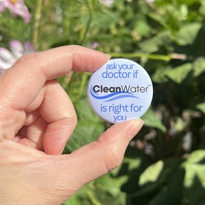 May include: A round, light blue pin-back button featuring the dark blue text 'ask your doctor if' at the top, the word 'CleanWater' in black with a blue wave graphic in the center, and 'is right for you' in dark blue at the bottom.