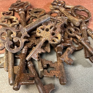 May include: A pile of antique keys, all rusted and worn, with intricate designs and varying sizes. The keys are arranged in a random pattern, showcasing their unique shapes and textures.