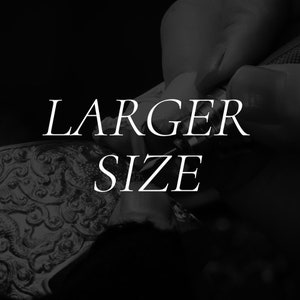 以下が含まれることがあります： 銀色の装飾的なオブジェクトのクローズアップ。白い文字で「LARGER SIZE」と書いてあります。