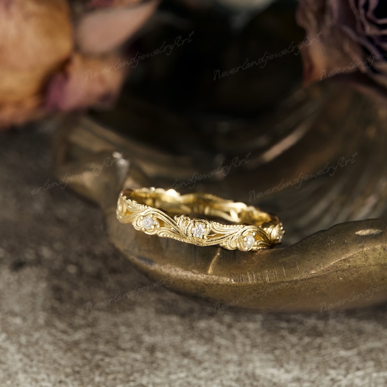 Puede incluir: Un delicado anillo de banda de oro con un dise&ntilde;o floral y peque&ntilde;os diamantes engastados en la banda.