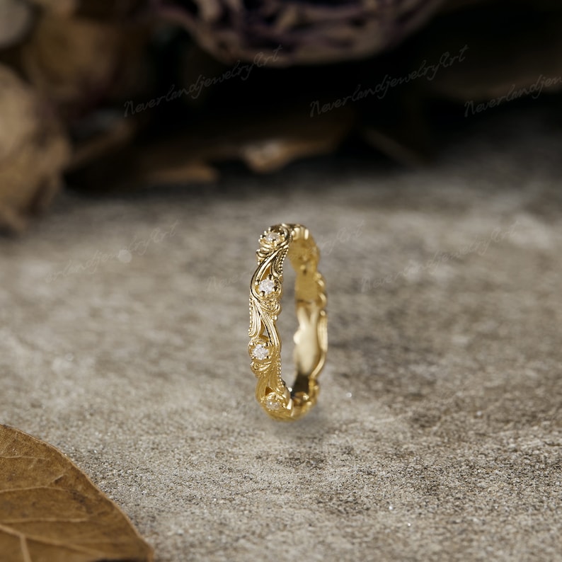 Puede incluir: Una fina banda de boda de oro con un dise&ntilde;o floral y peque&ntilde;os diamantes. La banda es delgada y tiene un aspecto delicado y femenino.