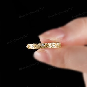 Puede incluir: Un delicado anillo de banda de oro con un dise&ntilde;o floral y peque&ntilde;as piedras preciosas transparentes.