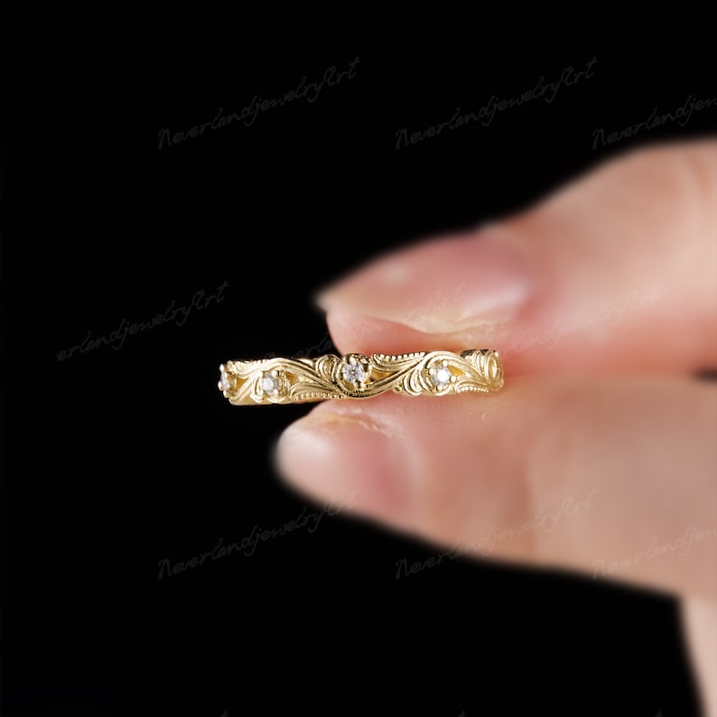 Puede incluir: Un delicado anillo de banda de oro con un dise&ntilde;o floral y peque&ntilde;as piedras preciosas transparentes.