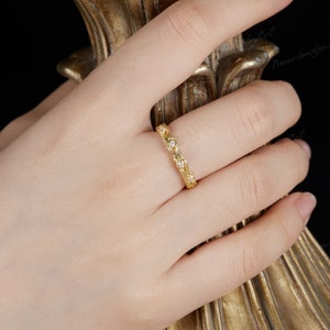 Puede incluir: Un anillo de banda de oro con un delicado dise&ntilde;o floral y peque&ntilde;as piedras transparentes.