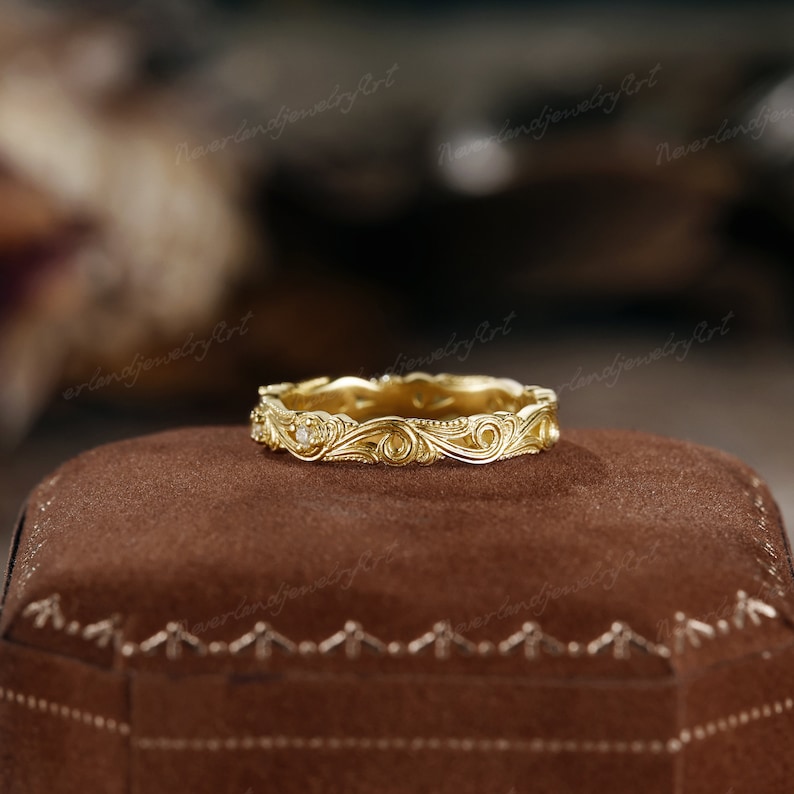 Puede incluir: Una banda de boda de oro con un dise&ntilde;o delicado e intrincado que presenta un patr&oacute;n floral y un peque&ntilde;o acento de diamante.