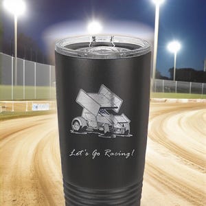 以下が含まれることがあります： レースカーと「Let's Go Racing!」のテキストが銀色に彫刻された黒いステンレス製のタンブラー