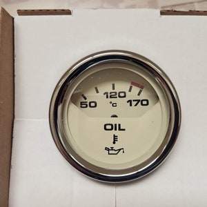 Peut inclure: Un indicateur de température d'huile blanc avec une lunette chromée. Le cadran de l'indicateur comporte des marques et du texte noirs, notamment "OIL" et "120°C".