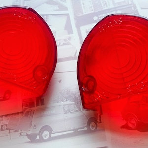 May include: Two red plastic car tail light lenses with a circular pattern. The lenses are designed for a classic car.