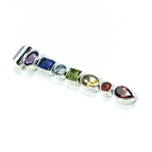 Puede incluir: Un colgante de plata con una fila de piedras preciosas de colores, incluyendo amatista, zafiro, aguamarina, peridoto, citrino, cornalina y granate.