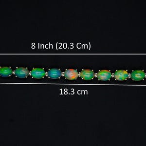 May include: A bracelet featuring a series of oval-shaped iridescent stones in shades of green, blue, and orange, set in a silver-toned metal chain. The total length is 20.3 cm, with a 2.0 cm extender chain and an 18.3 cm main section.