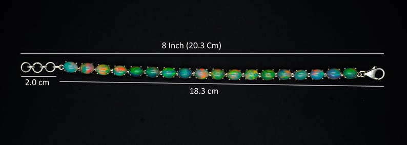 May include: A bracelet featuring a series of oval-shaped iridescent stones in shades of green, blue, and orange, set in a silver-toned metal chain. The total length is 20.3 cm, with a 2.0 cm extender chain and an 18.3 cm main section.
