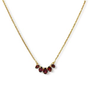 May include: A gold chain necklace with a cluster of five red oval-shaped gemstones.