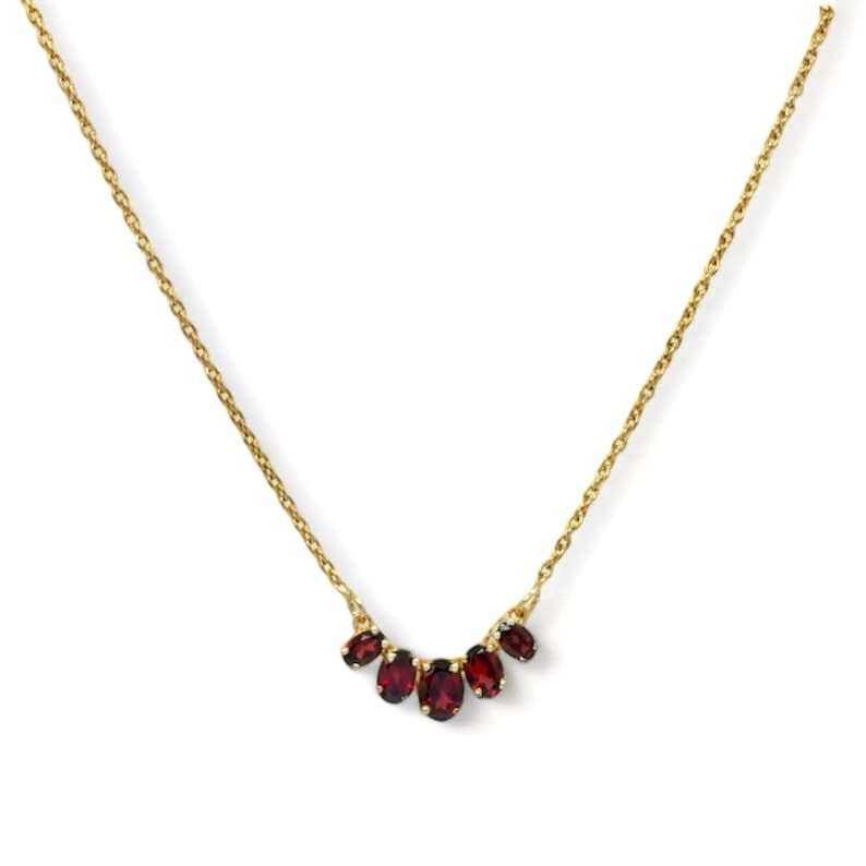 May include: A gold chain necklace with a cluster of five red oval-shaped gemstones.