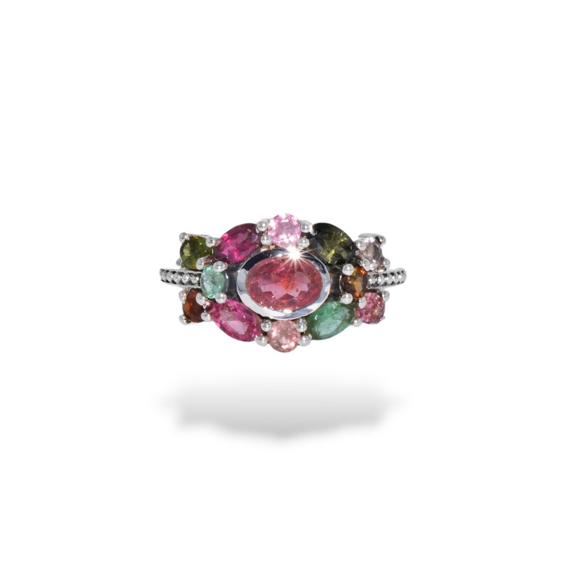 K&ouml;nnte beinhalten: Ein silberner Ring mit einem Cluster aus bunten Edelsteinen, darunter rosa, gr&uuml;n und braun. Der mittlere Stein ist ein gro&szlig;er, ovaler rosafarbener Edelstein.