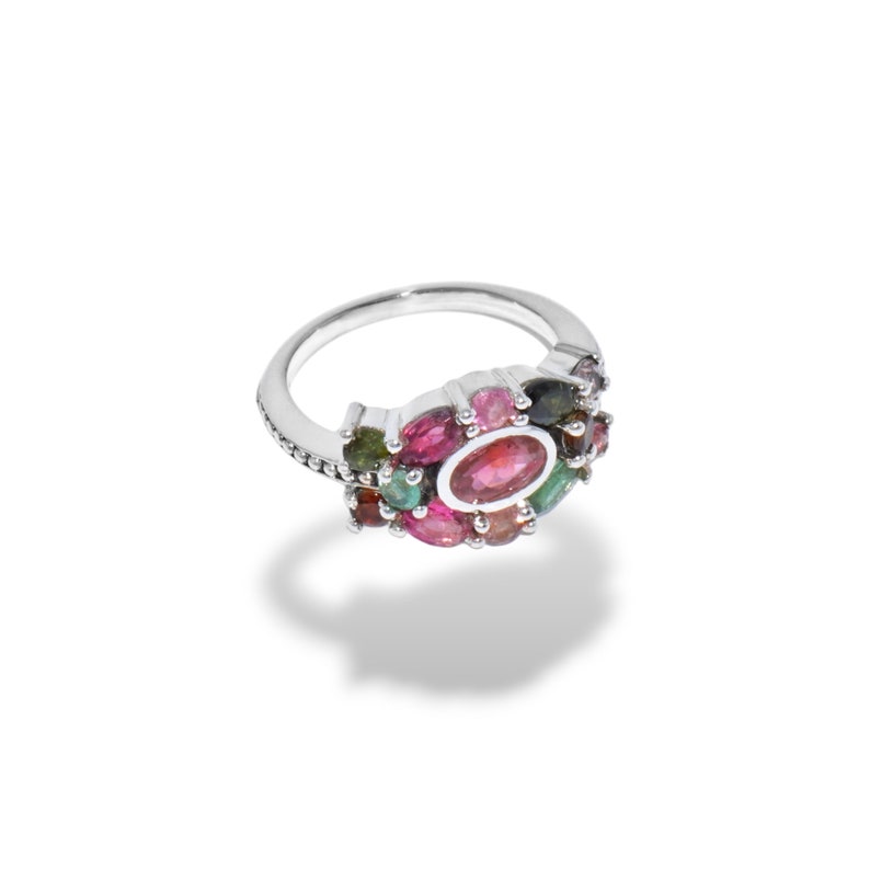 K&ouml;nnte beinhalten: Ein silberner Ring mit einem Cluster aus bunten Edelsteinen, darunter rosa, gr&uuml;n und lila.