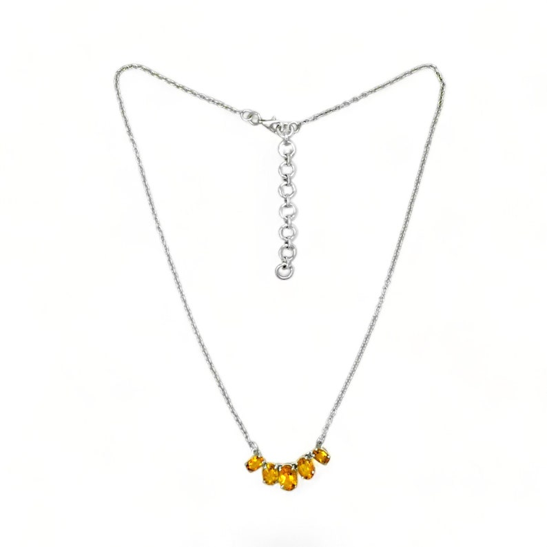 May include: A silver chain necklace with a delicate row of oval-shaped amber gemstones.