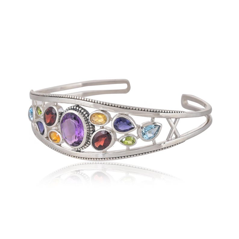 Puede incluir: Pulsera de plata con un dise&ntilde;o delicado que presenta una variedad de piedras preciosas de colores, incluyendo amatista, granate, peridoto y topacio.