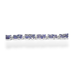 May include: A silver bracelet featuring a series of oval-shaped, deep blue gemstones. The gemstones are set closely together, creating a continuous pattern. The bracelet is displayed against a white background, highlighting the jewelry's design.