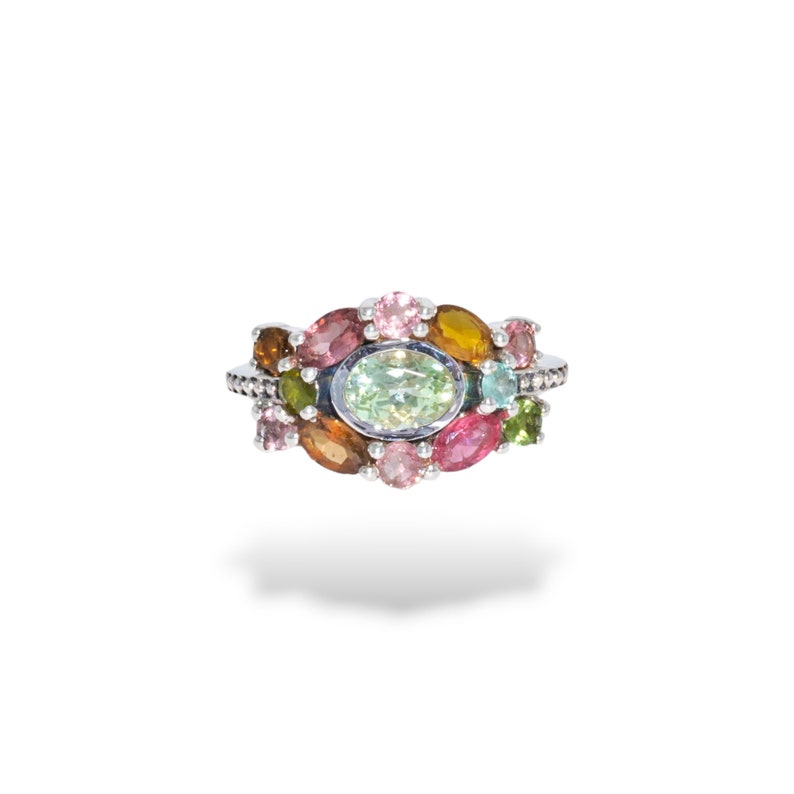K&ouml;nnte beinhalten: Ein silberner Ring mit einem Cluster aus bunten Edelsteinen, darunter rosa, gr&uuml;n, braun und gelb.