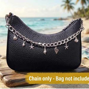 May include: A silver-toned metal chain featuring multiple dangling charms shaped like various seashells and starfish. The chain is draped across the front of a black textured handbag. The text "Chain only - Bag not included" is visible.