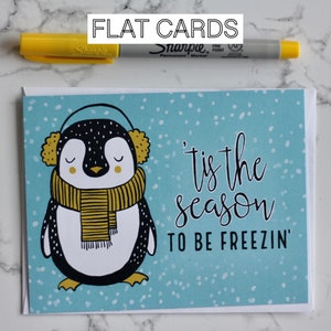 Grafischer niedlicher Pinguin, der Ohrenschützer und einen Schal im Schnee trägt Karte - Umschlag - innen blanko - Urlaub - “Tis the season to be freezin”