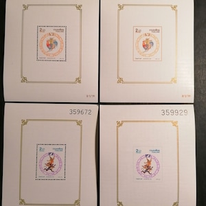 Può includere: Quattro francobolli thailandesi vintage con un gallo in un cerchio. I francobolli sono montati su cartoncino bianco con bordi dorati e i numeri 493531, 486334, 359672 e 359929 stampati in nero nella parte superiore di ogni scheda. Il testo "2 บาท" è stampato in nero nella parte inferiore di ogni scheda.
