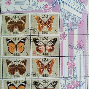 May include: Sheet of postage stamps from Dubai featuring colorful butterfly illustrations. The stamps have a light green background with the word "DUBAI" and the value "60" printed on them. Decorative floral and architectural elements are also present.