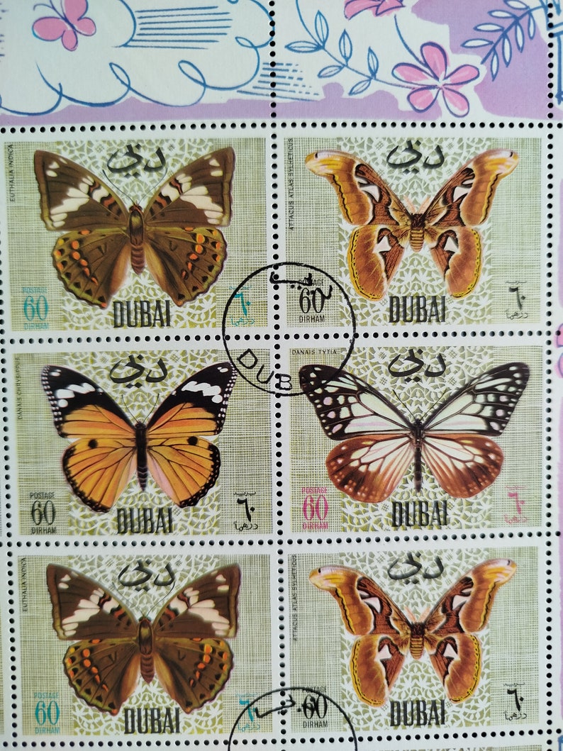 May include: A sheet of postage stamps featuring colorful butterfly illustrations. Each stamp displays the word "DUBAI" and the value "60 DIRHAM". The stamps showcase various butterfly species with detailed wing patterns.
