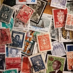 May include: A collection of vintage postage stamps from around the world. The stamps feature a variety of designs, including animals, flags, and portraits. Some of the stamps are in color, while others are in black and white. The stamps are arranged in a random pattern on a black background.