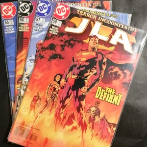 Può includere: Una pila di fumetti con la Justice League of America. La copertina del fumetto in cima è rossa e arancione con il testo "JLA" in grandi lettere bianche. Il testo "Terror Incognita Part 1 of 4" è anche visibile sulla copertina. La copertina presenta Superman con un costume rosso e blu, in piedi davanti a uno sfondo infuocato. Il testo "The Defiant" è visibile nell'angolo in basso a destra della copertina.