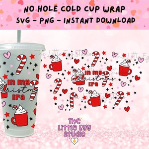 Könnte beinhalten: Ein digitales Design für eine kalte Becherhülle mit einem roten und weißen Zuckerstangen, einem roten Becher mit Schlagsahne und dem Text "In my Christmas Era". Das Design ist auf einem rosa Hintergrund mit weißen Sternen und Herzen.