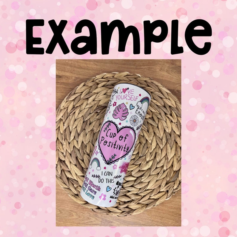 Peut inclure: Un gobelet en acier inoxydable blanc avec un c&oelig;ur rose et le texte "Cup of Positivity" entour&eacute; de gribouillis color&eacute;s et de phrases inspirantes comme "Love Yourself" et "I Can Do This".