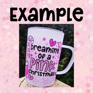 K&ouml;nnte beinhalten: Eine wei&szlig;e Keramiktasse mit einem rosafarbenen Design, auf dem "dreaming of a pink christmas" steht. Das Design enth&auml;lt Zuckerstangen, Sterne und Herzen.