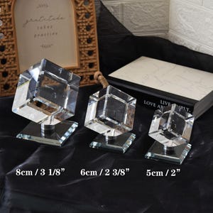 Pode incluir: Três esculturas de cubo de cristal transparente de tamanhos variados, cada uma montada em uma base quadrada. A maior tem 8 cm de altura, a do meio 6 cm e a menor 5 cm. O texto "gratitude takes practice" é visível no fundo.