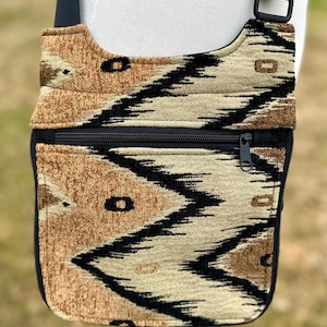 May include: A brown and black patterned crossbody bag with a zippered pocket and a black adjustable strap.