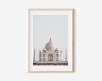 May include: Framed print of the Taj Mahal, a white marble mausoleum in India. The image shows the iconic building with its central dome, minarets, and detailed architecture. The print is set in a light-coloured wooden frame.