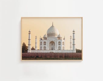May include: A framed print depicting the Taj Mahal, a white marble mausoleum in India. The image shows the iconic building with its central dome, minarets, and a red brick base. The background is a warm, golden-yellow sky.